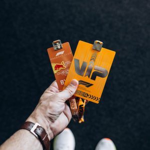 Close-up of a hand holding two VIP event badges against a black background.